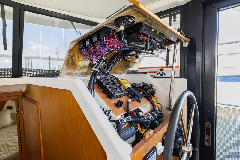 Slide: The Image of 2019 Beneteau Swift Trawler 35 helm station with exposed wiring and controls. - 13