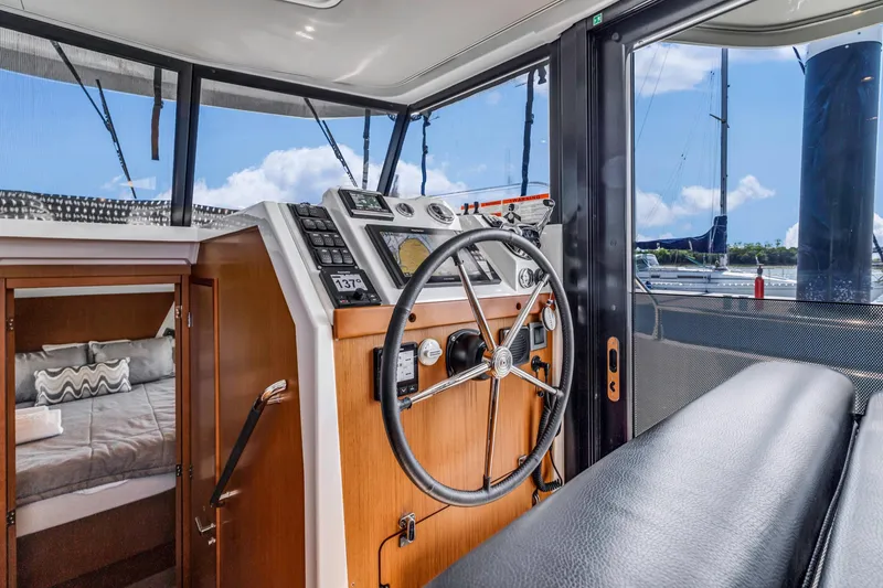Slide: The Image of 2019 Beneteau Swift Trawler 35 interior with helm, cabin, and marina view. - 17