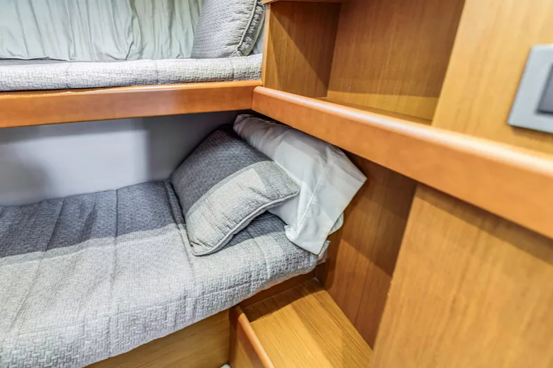 Slide: The Image of Cozy bunk bed in 2019 Beneteau Swift Trawler 35 cabin, featuring wooden accents and gray bedding. - 26