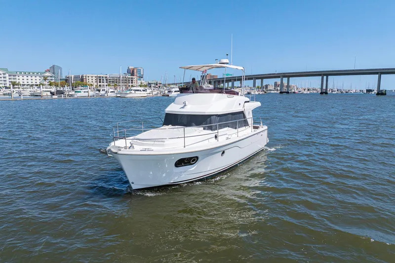 Slide: The Image of 2019 Beneteau Swift Trawler 35 cruising in a marina with cityscape and bridge backdrop. - 53