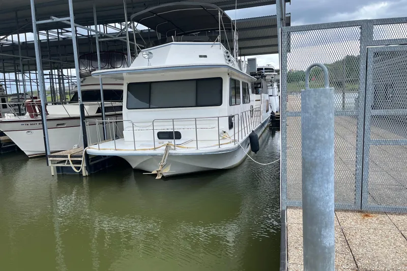The Image of A 1995 WaveLenth Wide Body boat docked in a marina under a covered structure. - 0