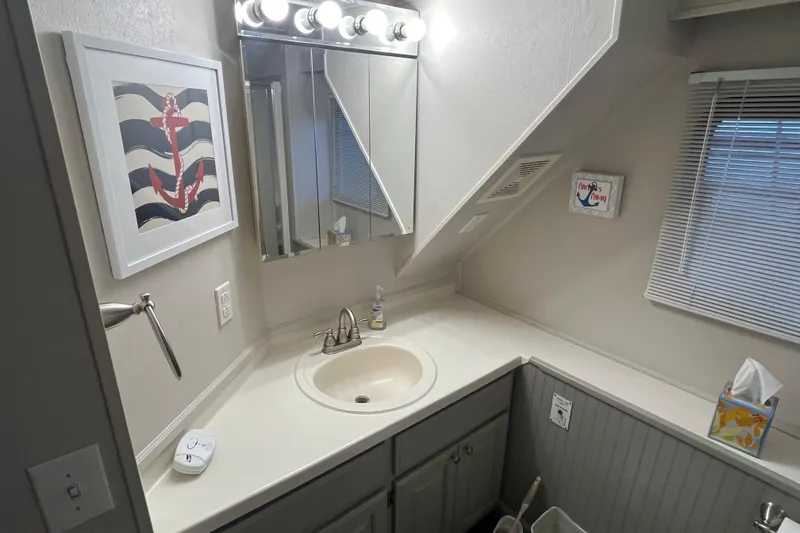 Slide: The Image of Small bathroom with nautical decor, featuring a mirror, sink, and anchor-themed artwork. - 15
