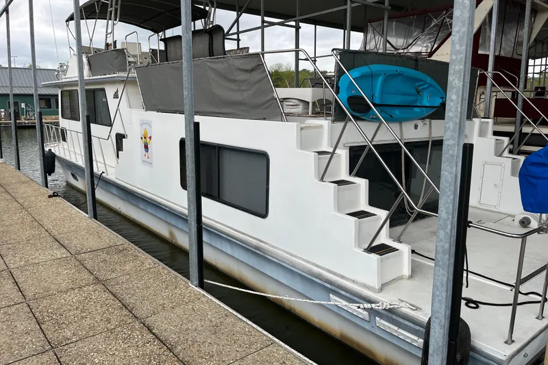 Slide: The Image of 1995 WaveLenth Wide Body houseboat docked, featuring stairs and a blue kayak. - 43