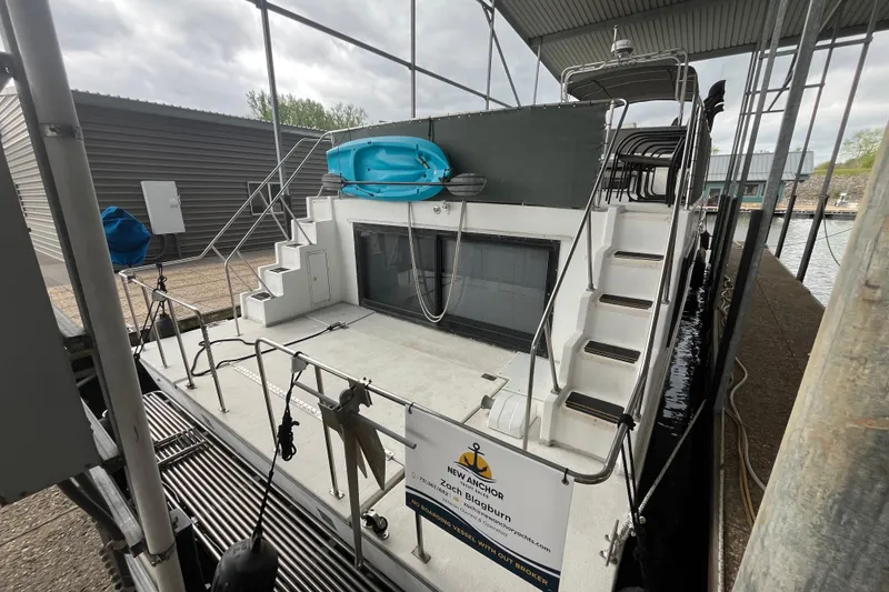 Slide: The Image of 1995 WaveLenth Wide Body boat docked, featuring dual staircases and a blue kayak on deck. - 44