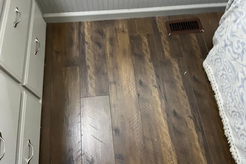 Slide: The Image of Wooden floor with vent, adjacent to cabinets and patterned bedspread. - 55