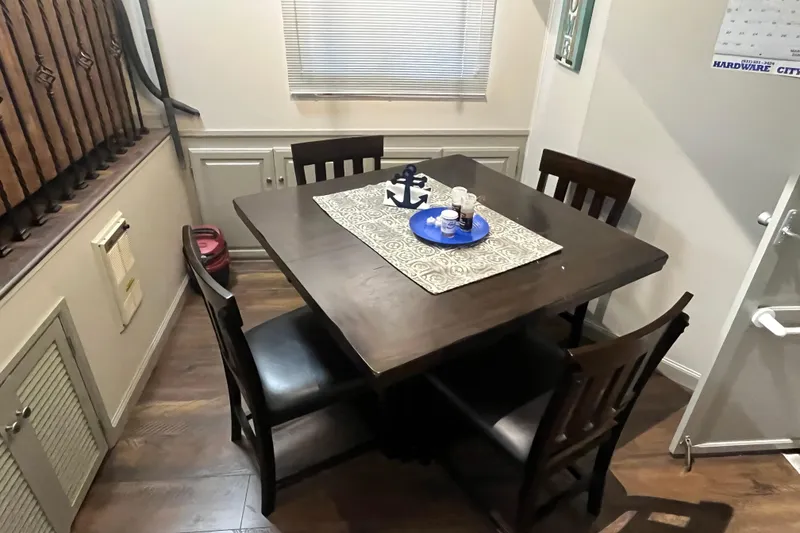 Slide: The Image of Dining area with dark wood table, four chairs, and nautical-themed centerpiece. - 7