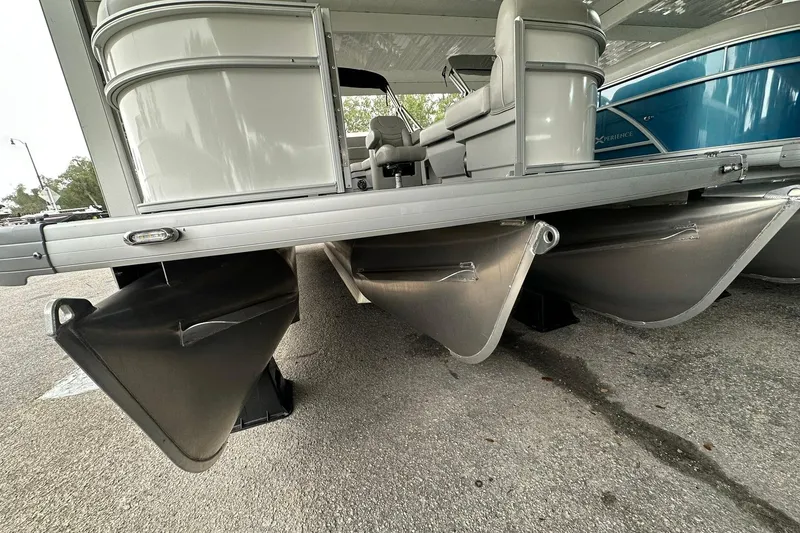 Slide: The Image of 2026 Sweetwater EX2086S pontoon boat undercarriage view in a parking area. - 2