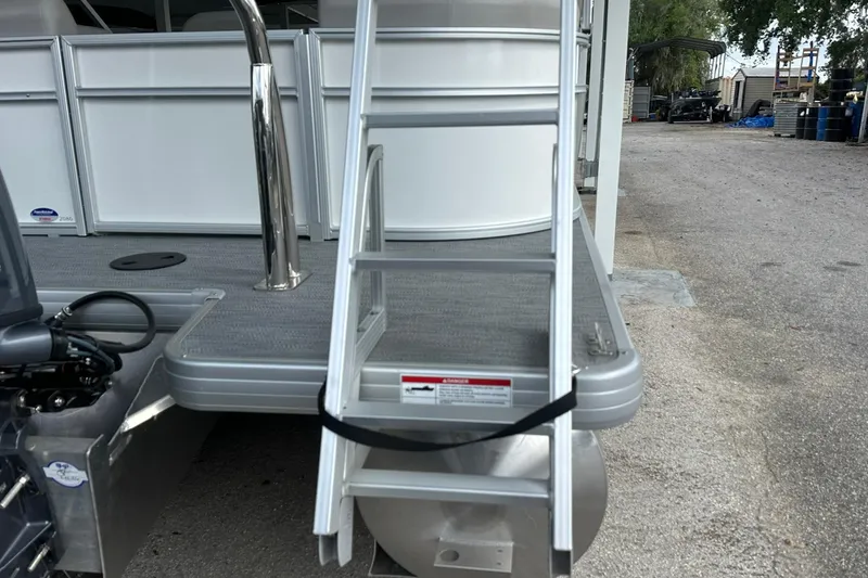 Slide: The Image of Sweetwater EX2086S 2026 boat with aluminum ladder and deck, parked outdoors. - 26