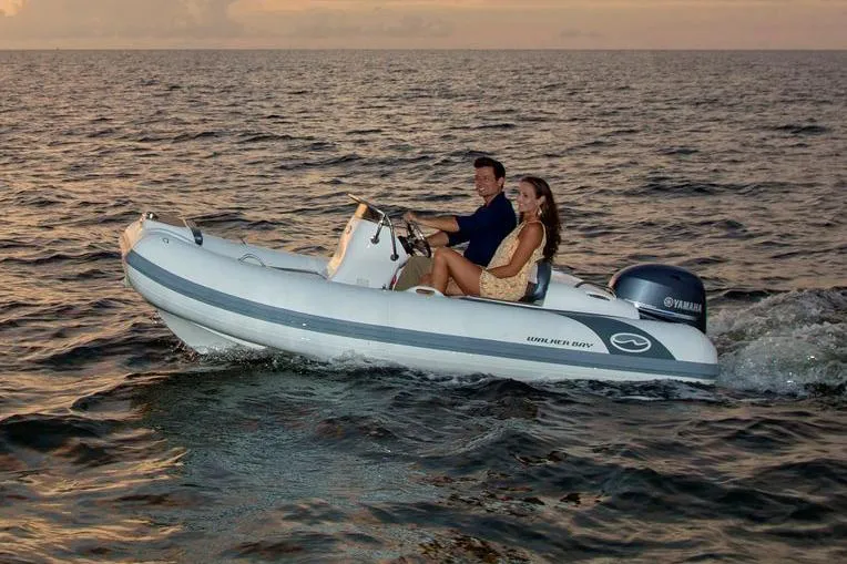 Slide: The Image of Manufacturer Provided Image: 2025 Walker Bay Generation 360 DLX boat cruising at sunset with two passengers. - 2