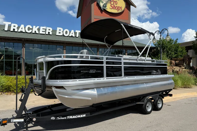 Slide: The Image of 2026 Sun Tracker SportFish 20 DLX pontoon boat on trailer outside Tracker Boats store. - 1