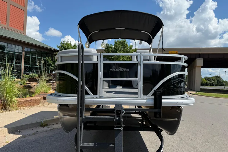 Slide: The Image of 2026 Sun Tracker SportFish 20 DLX pontoon boat on trailer, parked outdoors. - 2