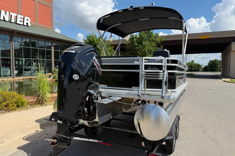 Slide: The Image of 2026 Sun Tracker SportFish 20 DLX pontoon boat with Mercury outboard motor, parked outdoors. - 9