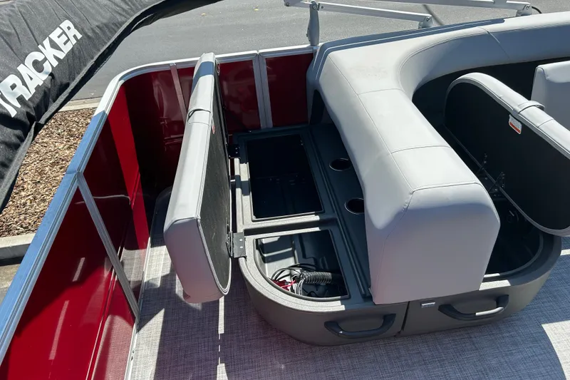 Slide: The Image of 2026 Sun Tracker Party Barge 18 DLX with open storage compartments and gray seating. - 15