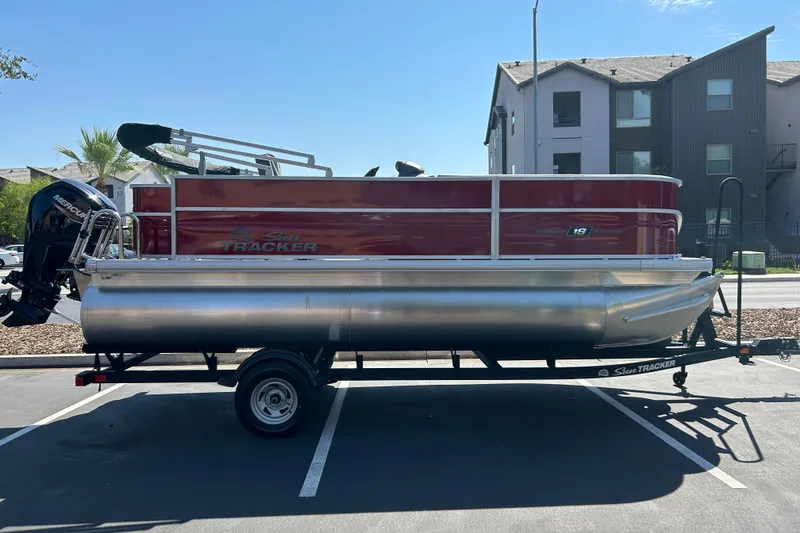 The Image of 2026 Sun Tracker Party Barge 18 DLX pontoon boat on trailer in parking lot. - 0