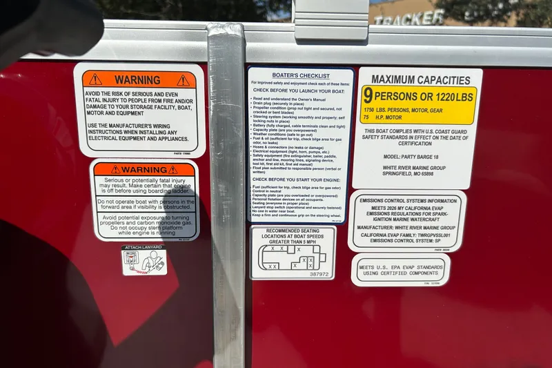 Slide: The Image of 2026 Sun Tracker Party Barge 18 DLX safety and capacity warning labels on red surface. - 19