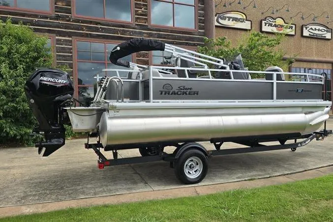 Slide: The Image of 2026 Sun Tracker Bass Buggy 18 DLX pontoon boat on trailer, parked outdoors. - 6