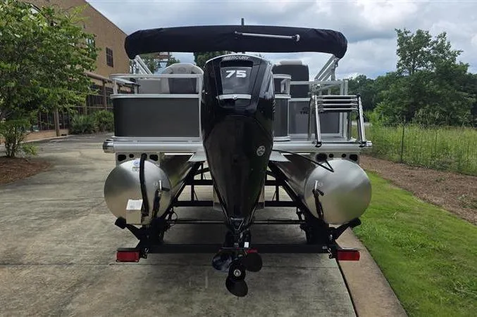 Slide: The Image of 2026 Sun Tracker Bass Buggy 18 DLX pontoon boat with 75 HP engine, parked outdoors. - 5