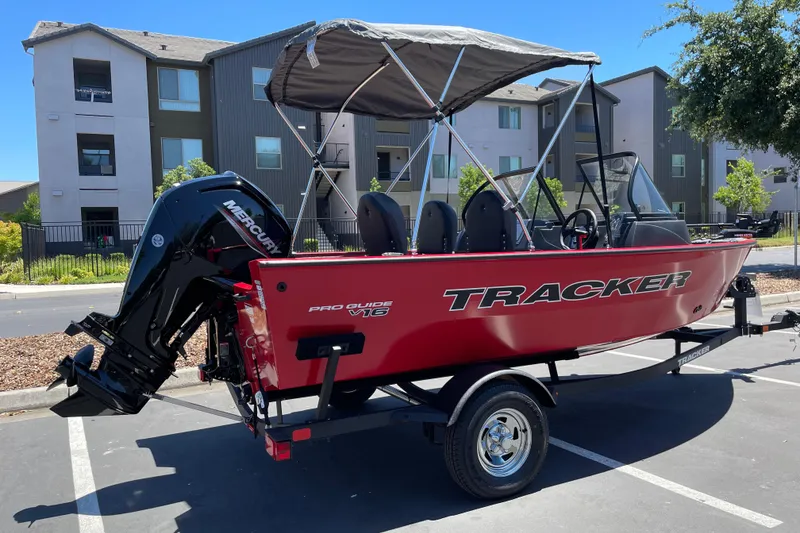 Slide: The Image of 2026 Tracker Pro Guide V-16 WT boat with canopy, parked outdoors. - 3