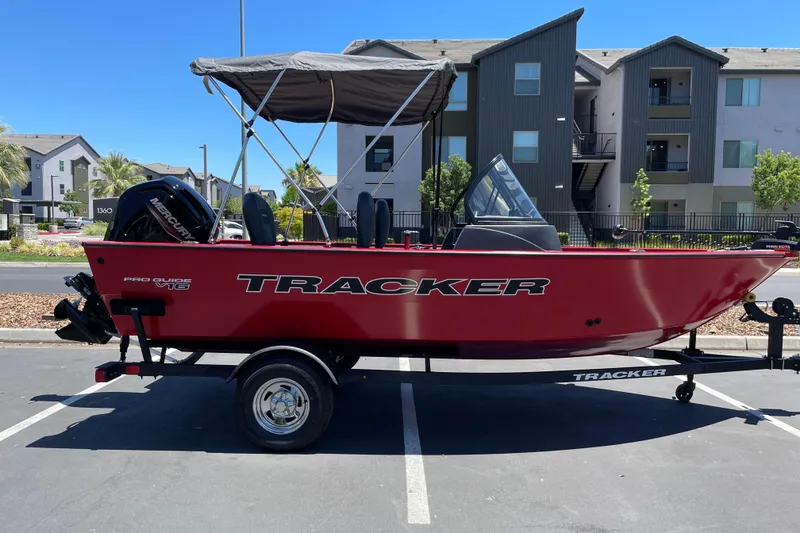 The Image of 2026 Tracker Pro Guide V-16 WT boat with canopy, parked in urban setting. - 0