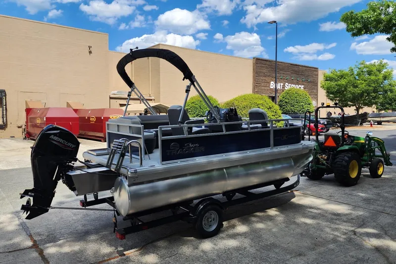 Slide: The Image of 2026 Sun Tracker Bass Buggy 16 XL Select pontoon boat on trailer near boat service. - 2