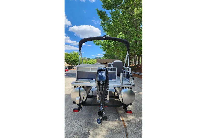 Slide: The Image of 2026 Sun Tracker Bass Buggy 16 XL Select pontoon boat with outboard motor, parked outdoors. - 3