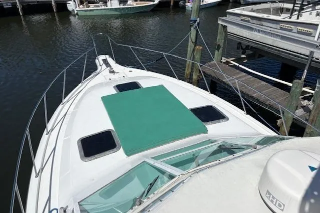 Slide: The Image of 1992 Tiara Yachts 3600 Open docked, featuring a green sunpad on the bow. - 6