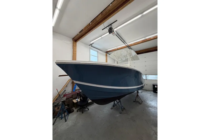Slide: The Image of 2017 Regulator 23 boat in a garage, blue hull, elevated on stands. - 5