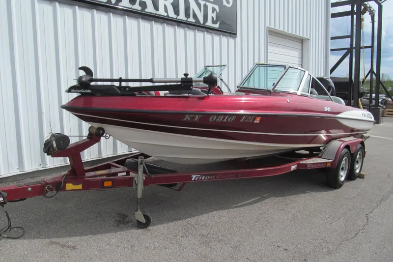 Slide: The Image of Red 2000 Triton SF-21 boat on trailer, parked outside a marine shop. - 2
