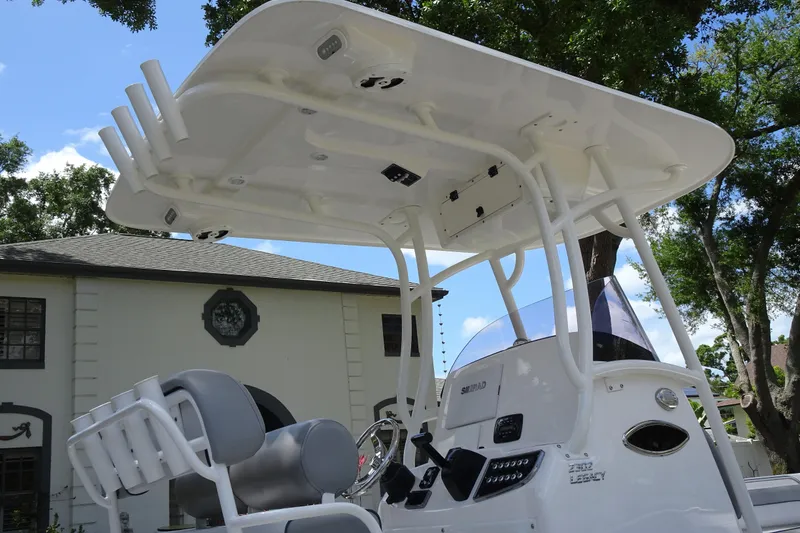 Slide: The Image of 2022 NauticStar 2302 Legacy boat with T-top and console, parked near a house. - 8