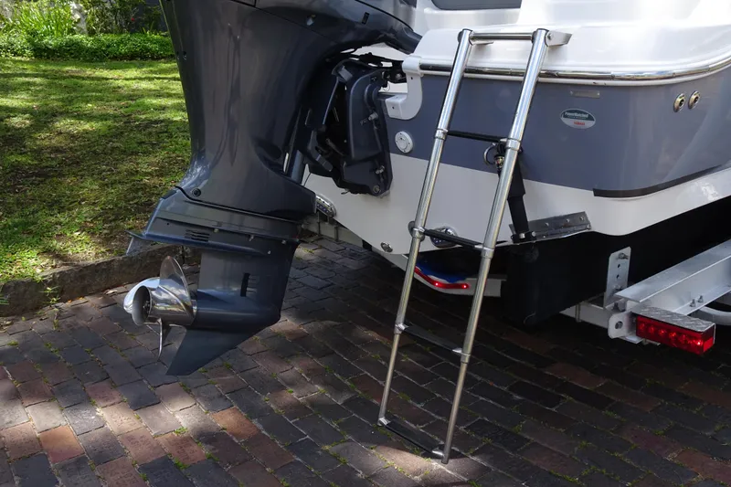 Slide: The Image of 2022 NauticStar 2302 Legacy boat with outboard motor and ladder on a brick driveway. - 9