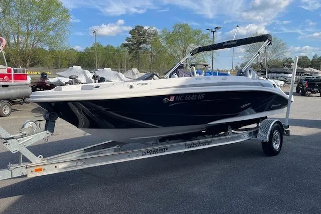 Slide: The Image of 2023 Hurricane SunDeck Sport 185 OB boat on trailer, parked outdoors under a blue sky. - 3