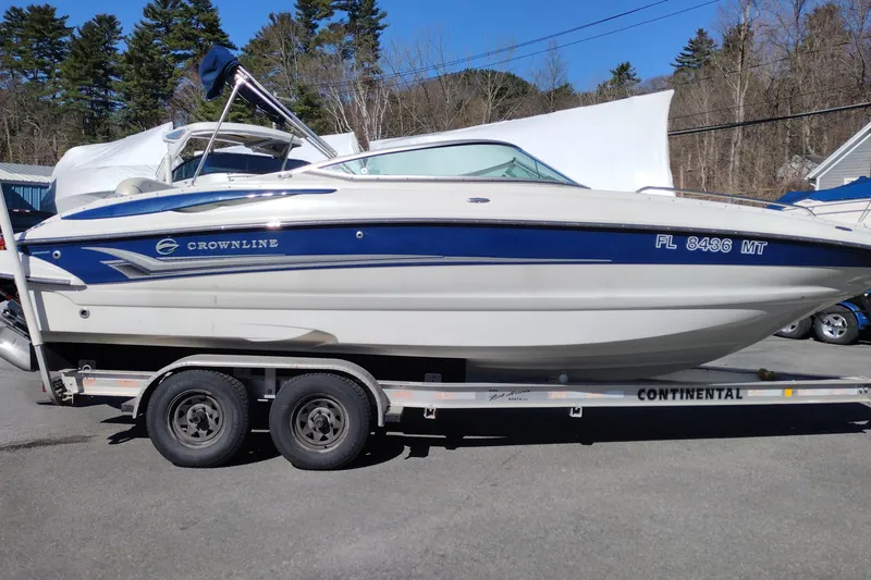 The Image of 2005 Crownline 240 EX boat on trailer, parked outdoors, with blue and white design. - 0