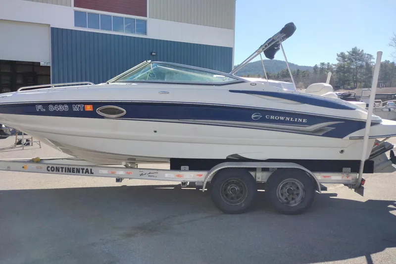 Slide: The Image of 2005 Crownline 240 EX boat on trailer, parked outdoors near a building. - 2