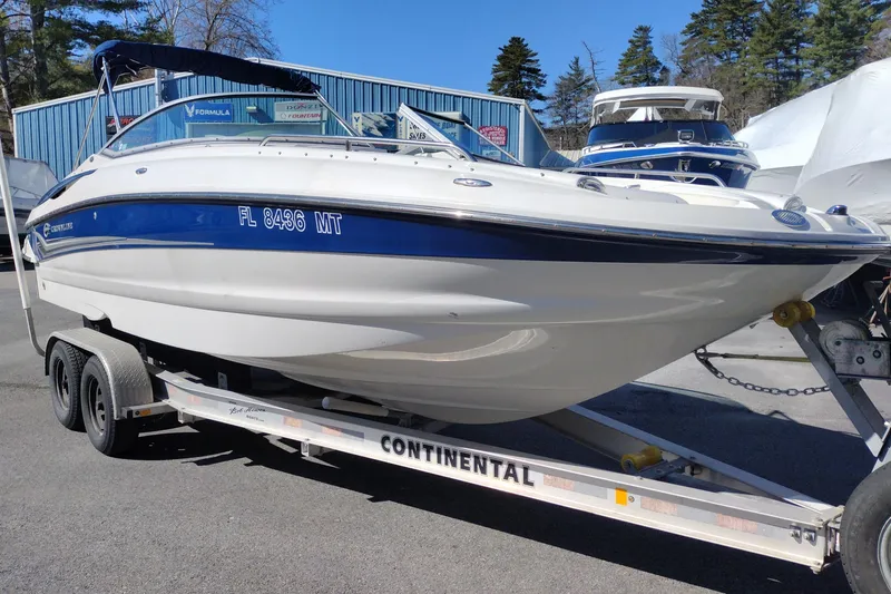 Slide: The Image of 2005 Crownline 240 EX boat on trailer, parked outdoors, with blue and white exterior. - 3