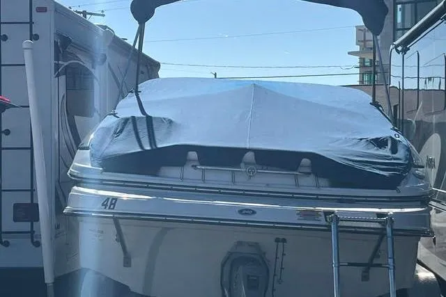 Slide: The Image of 2005 Crownline 240 EX boat with cover, parked between vehicles. - 40