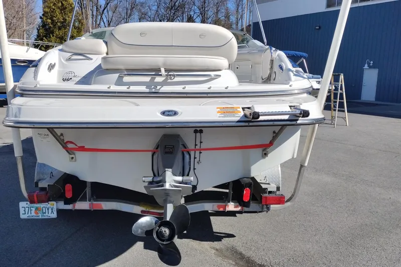 Slide: The Image of 2005 Crownline 240 EX boat rear view, parked on trailer in sunny outdoor setting. - 5