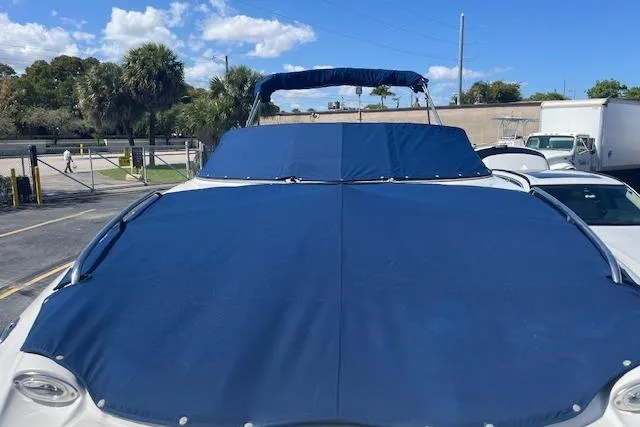 Slide: The Image of 2005 Crownline 240 EX boat with blue cover, parked outdoors under a clear sky. - 8