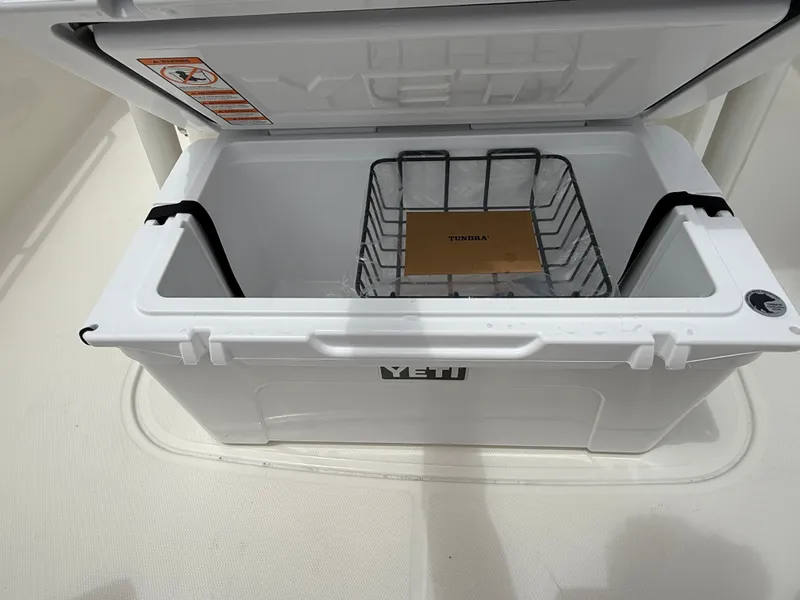 Slide: The Image of An open Yeti cooler on a boat with a wire basket and a manual inside. - 12