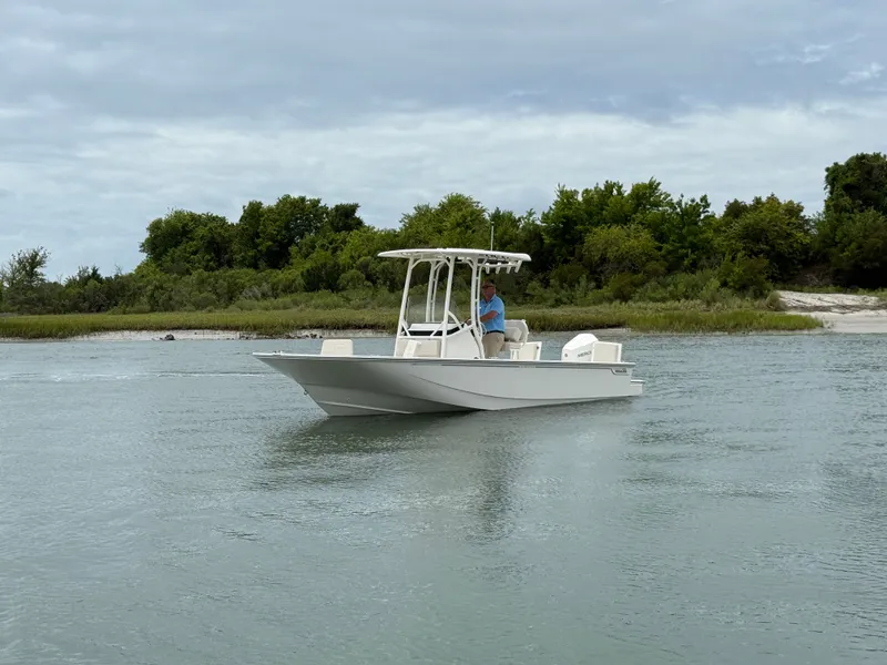 Slide: The Image of A 2026 Boston Whaler 210 Montauk on calm water, surrounded by green vegetation. - 7