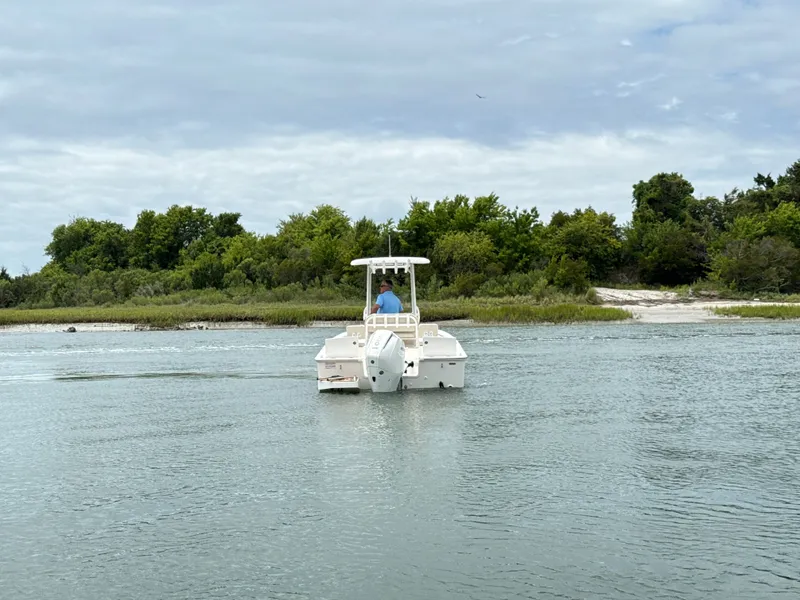 Slide: The Image of A 2026 Boston Whaler 210 Montauk on calm water with a green shoreline in the background. - 3