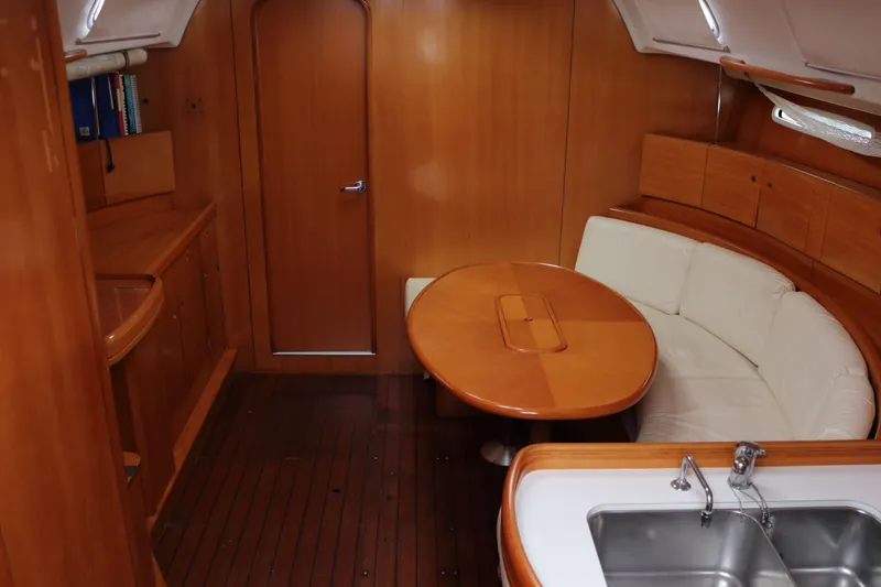 Slide: The Image of Interior of 2005 Beneteau First 47.7 yacht with wooden furnishings and white seating. - 16