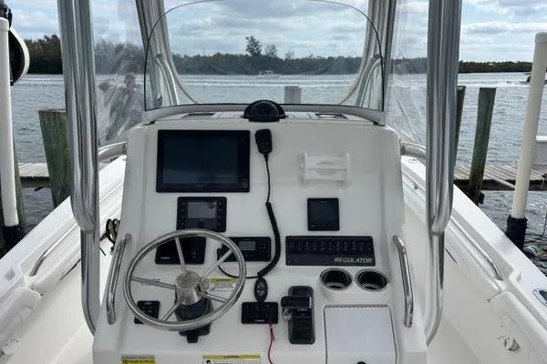 Slide: The Image of 2018 Regulator 23 Forward Seating boat dashboard with steering wheel and navigation equipment. - 18