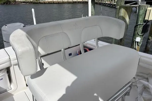 Slide: The Image of 2018 Regulator 23 Forward Seating boat with white cushioned seats by the water. - 28