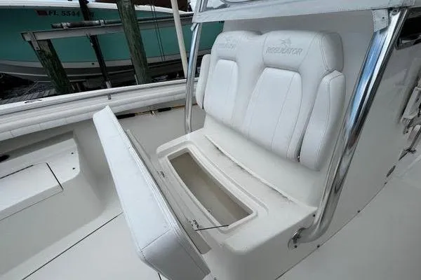 Slide: The Image of 2018 Regulator 23 Forward Seating boat with white cushioned seats and storage compartment. - 31