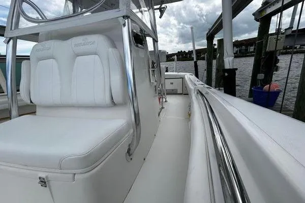 Slide: The Image of 2018 Regulator 23 Forward Seating boat docked, featuring sleek white seating and polished railings. - 40