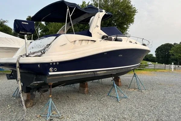 Slide: The Image of 2006 Sea Ray 340 Sundancer boat on stands, blue and white exterior, parked outdoors. - 4