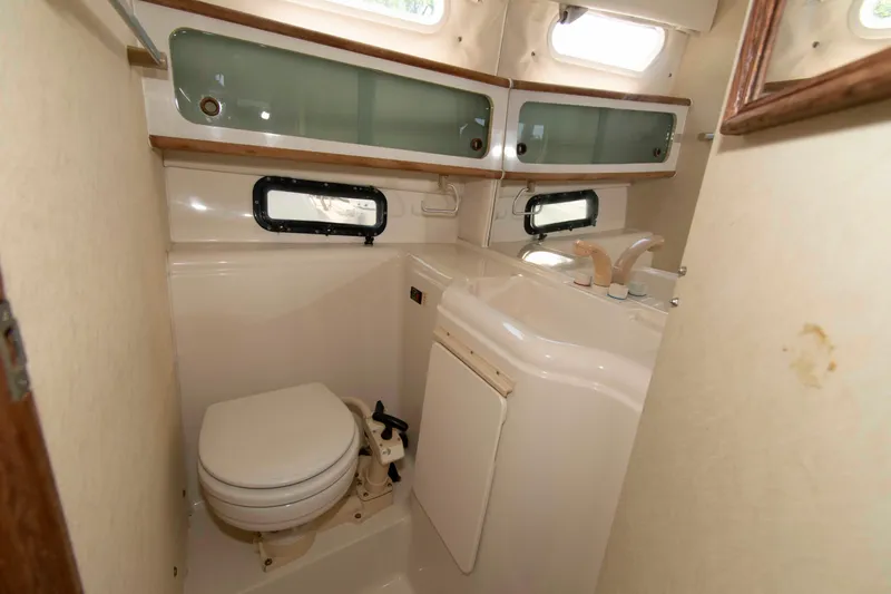 Slide: The Image of 1994 Bayliner 2855 Ciera boat bathroom with toilet, sink, and storage cabinets. - 11