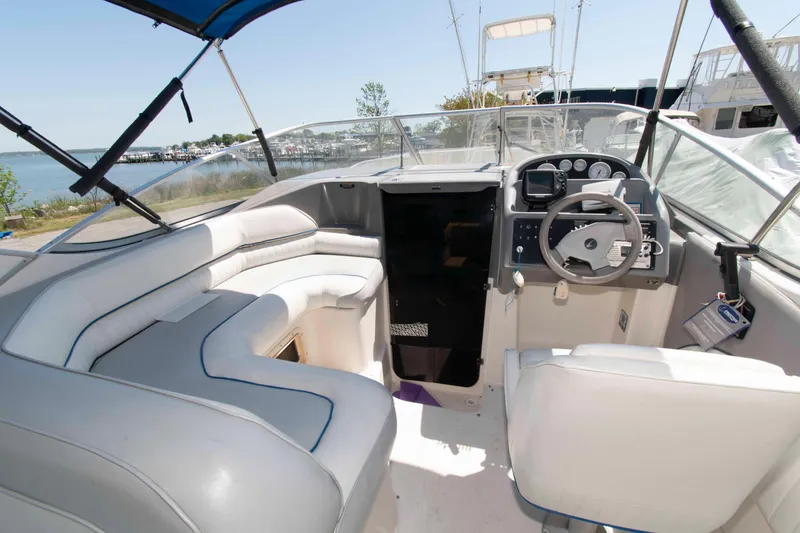 Slide: The Image of 1994 Bayliner 2855 Ciera boat interior with white seating and steering console, docked by the water. - 3