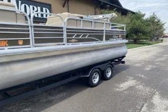 Slide: The Image of 2023 Sun Tracker SportFish 22 DLX pontoon boat on trailer, parked outdoors. - 13