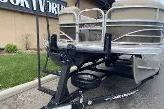 Slide: The Image of 2023 Sun Tracker SportFish 22 DLX pontoon boat on trailer, parked outside a building. - 14